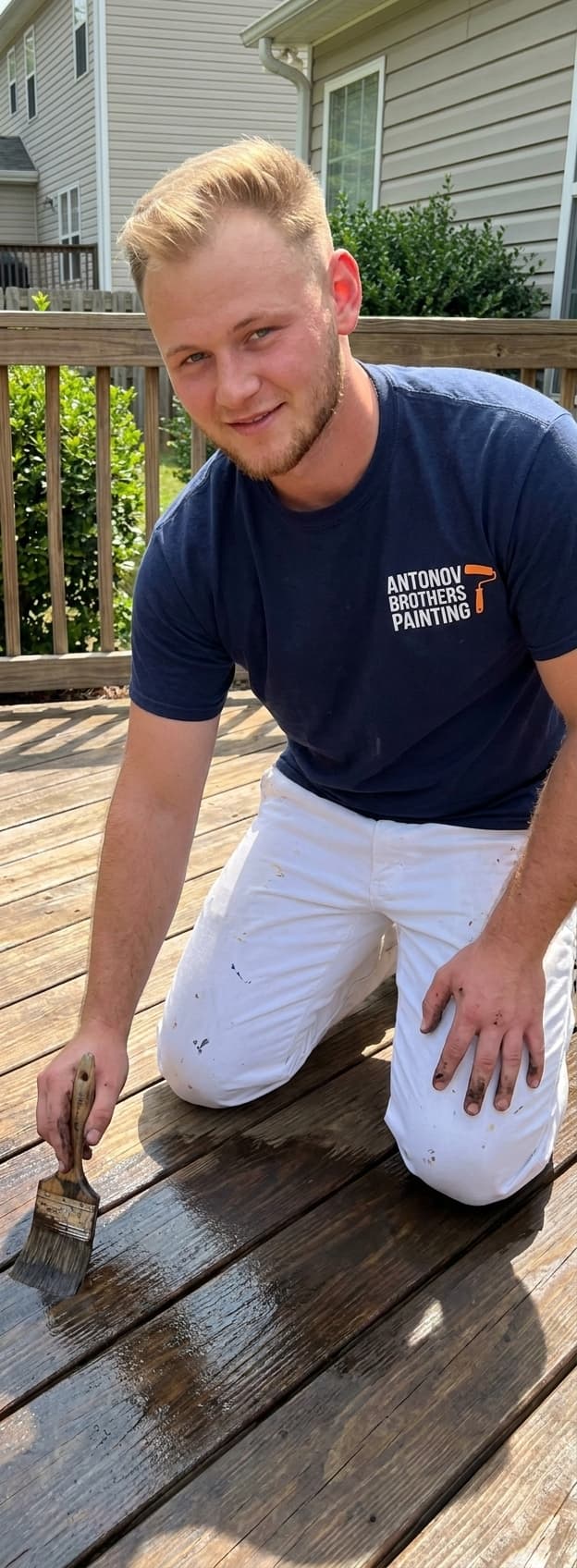Antonov Brothers painter brushing rich stain onto deck boards in Jacksonville